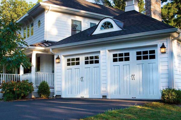 solid wood garage doors with windows and black handles on colonial home