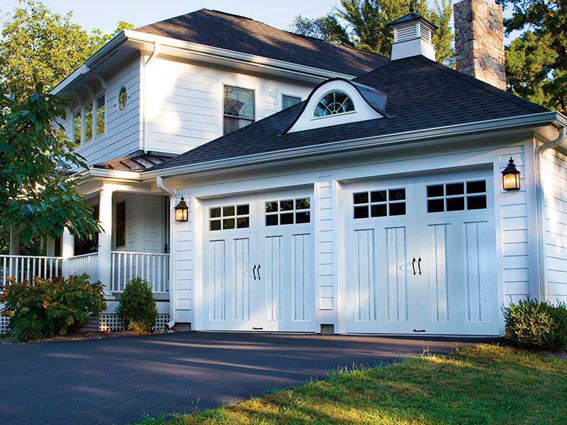 solid wood garage doors with windows and black handles on colonial home