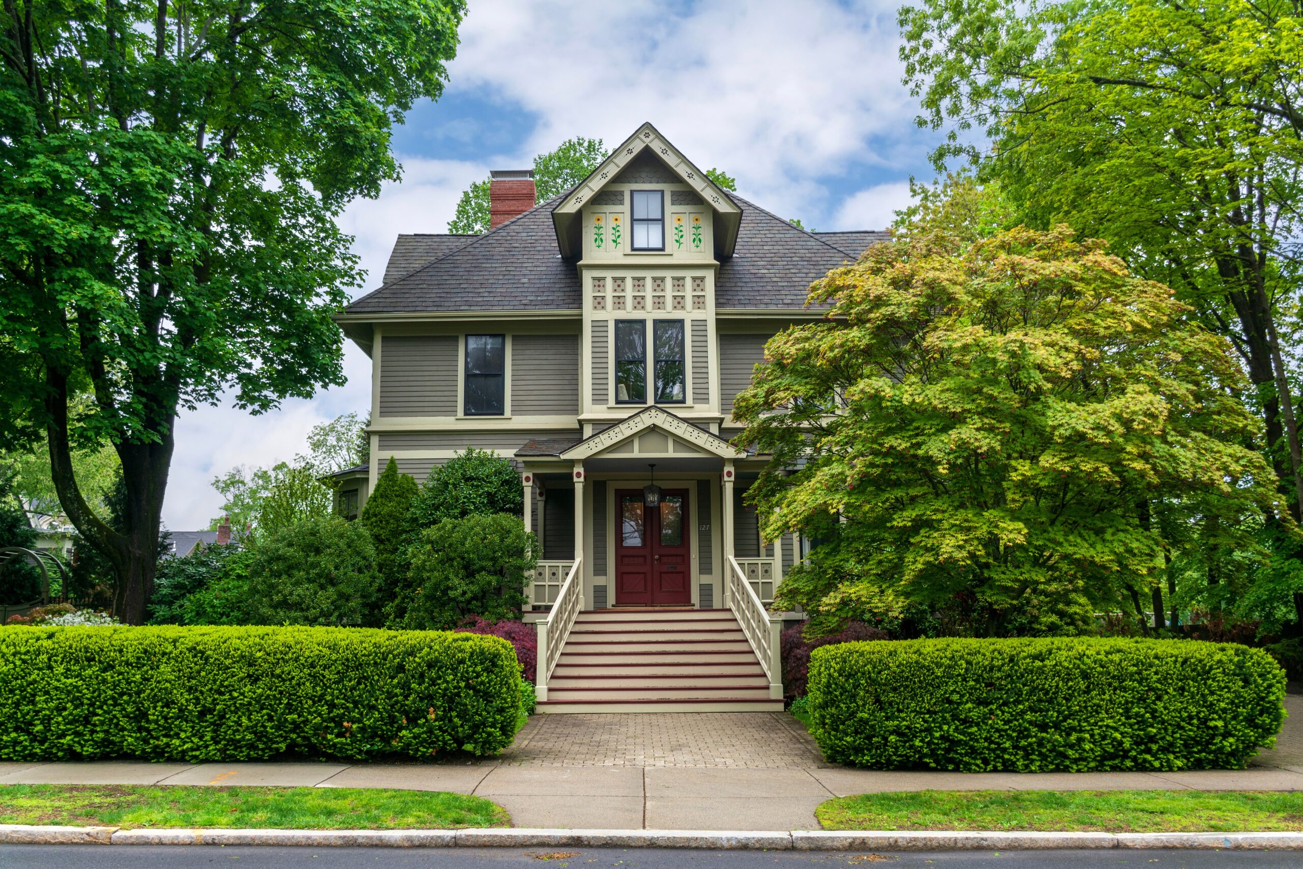 historic victorian family home surrounded by greenery with a victorian styles of garage doors
